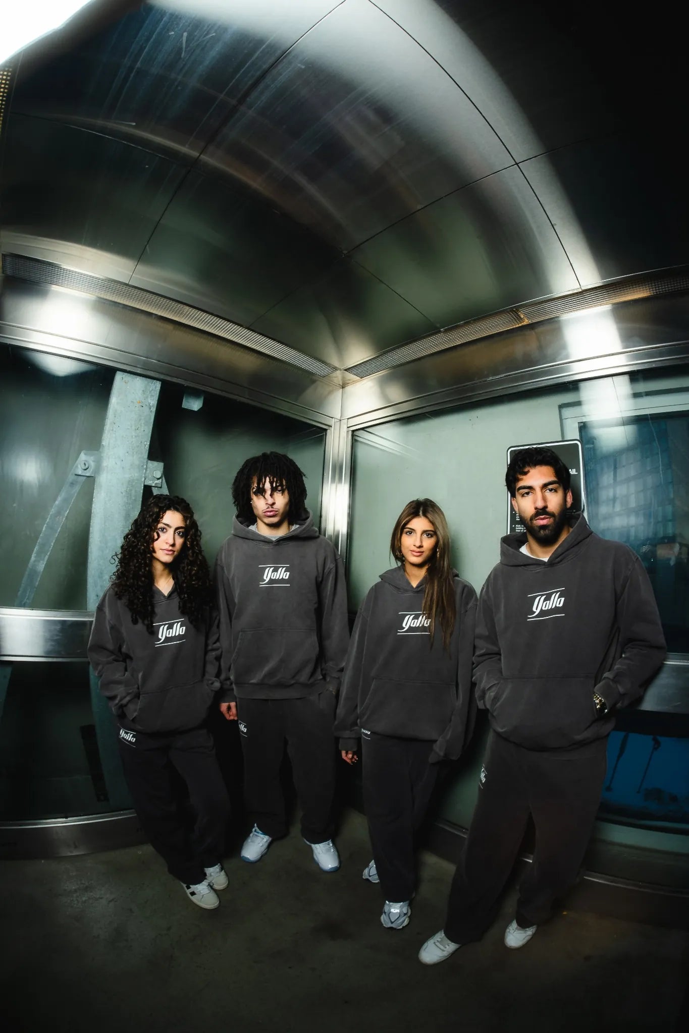 Group of models wearing matching dark grey Timeless Arab Tracksuits by Yalla Apparel, showcasing high-quality Arab streetwear & Arab Clothing in a modern urban setting.
