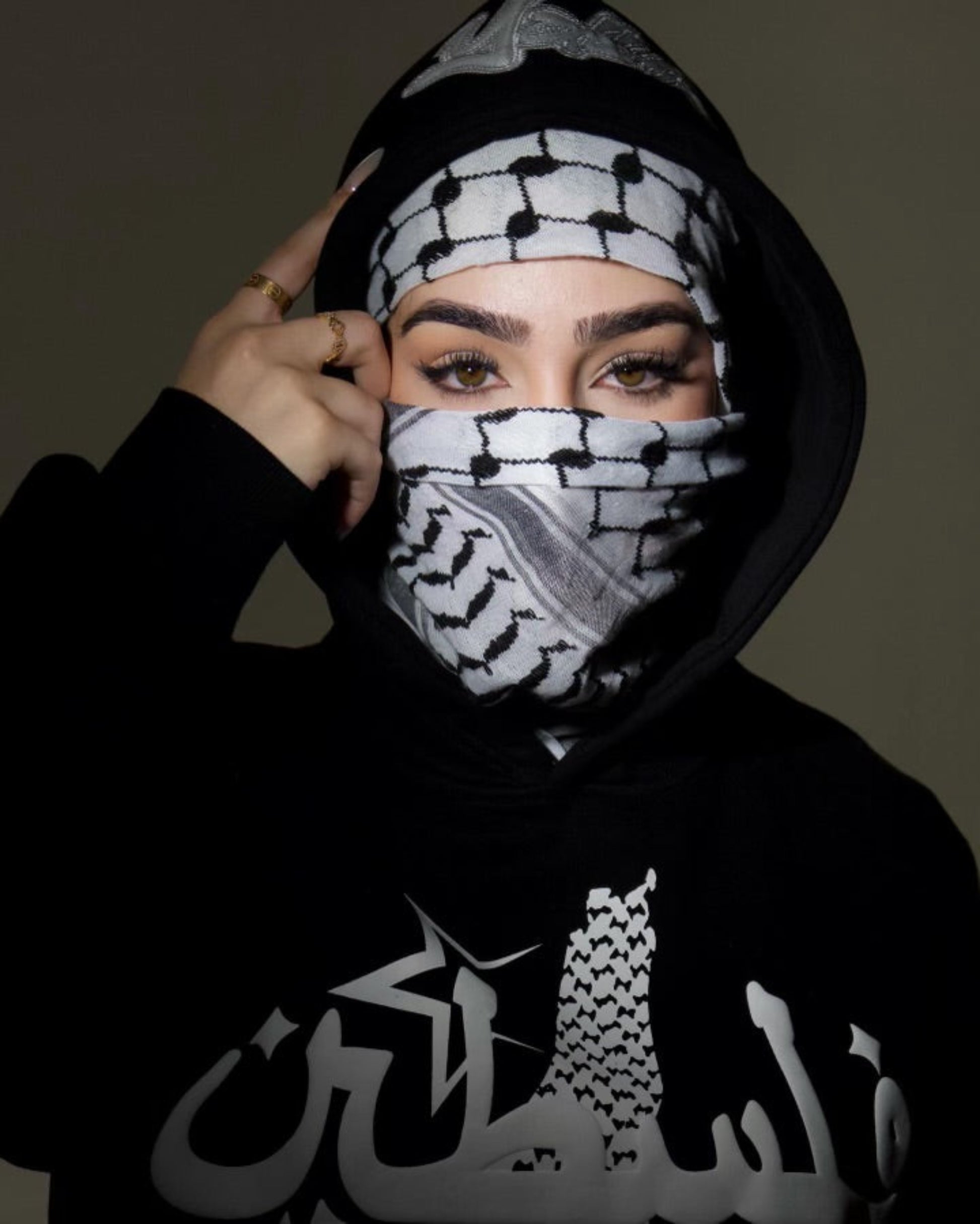 Influencer Adolla styling the Peace Black Hoodie with a Kufiya scarf, blending Palestinian heritage with streetwear fashion."