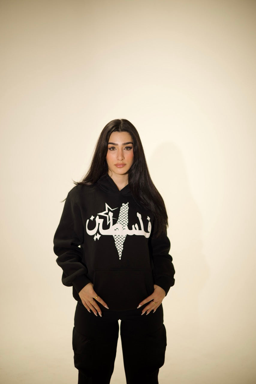 Model wearing Peace Black Hoodie, a modern Arab streetwear piece with Kufiya-inspired design and Arabic typography.