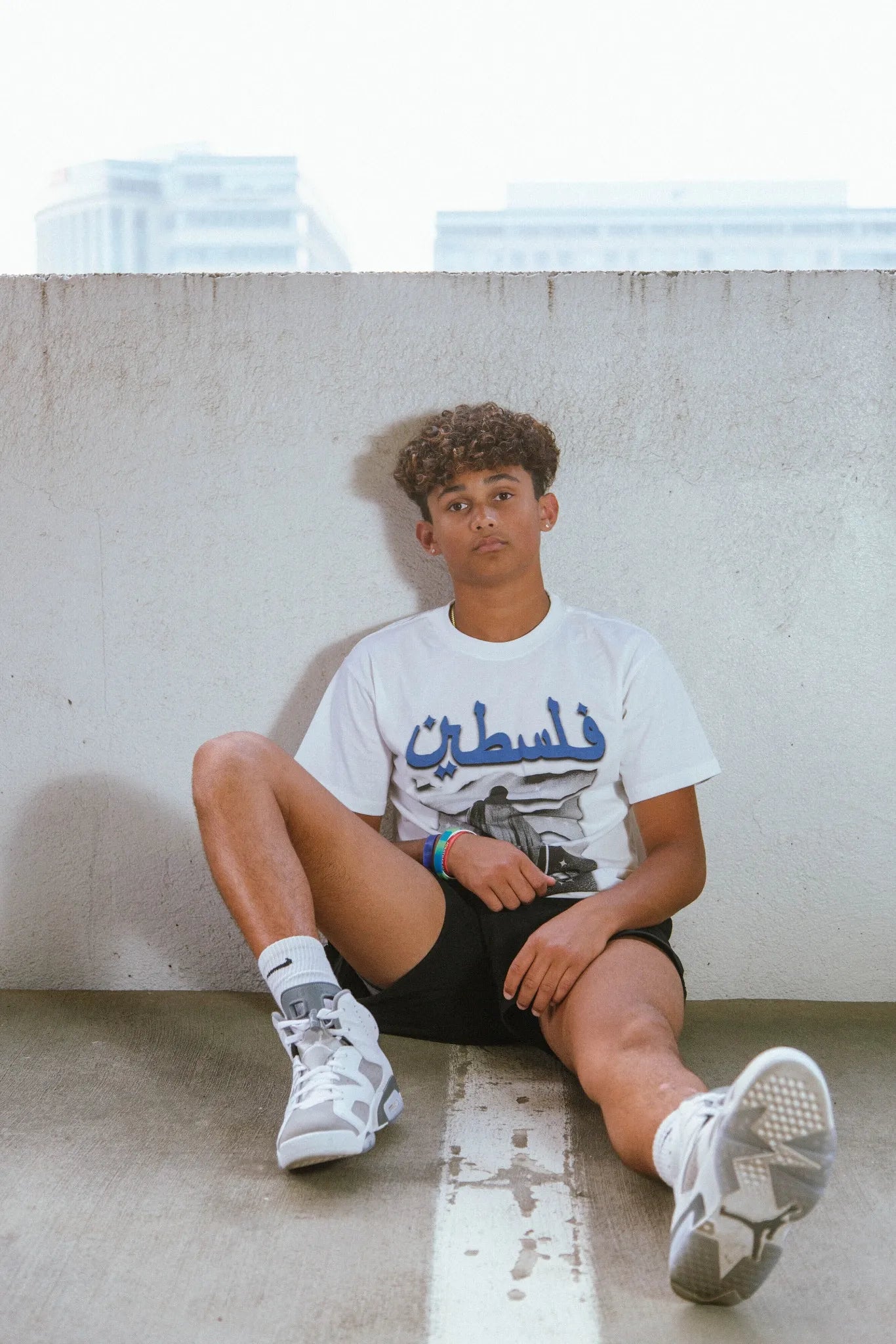 Model wearing the Snow Palestine Graphic Tee outdoors, showcasing the bold Palestinian-inspired design in high-quality, breathable cotton for a modern fashion statement.