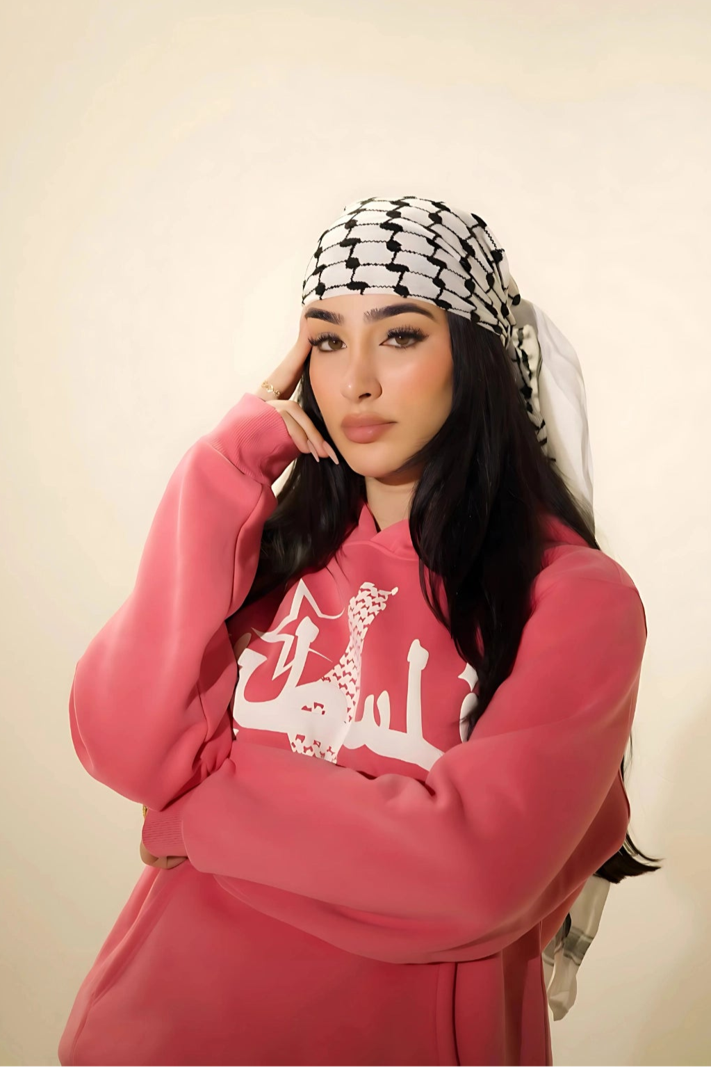 Influencer Adolla wearing the peace pink Palestine hoodie with Arabic calligraphy design. Inspired by Palestinian heritage and modern streetwear. Oversized, comfortable fit, styled with a traditional Kufiya headscarf.