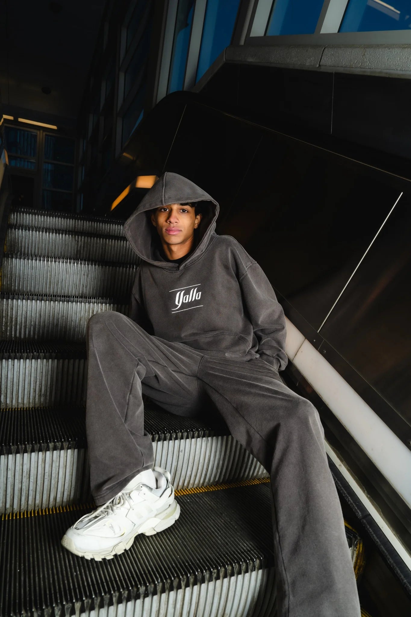 Model wearing full Timeless Arab Hoodie set while seated on escalator, showcasing heavyweight cotton Arab streetwear.